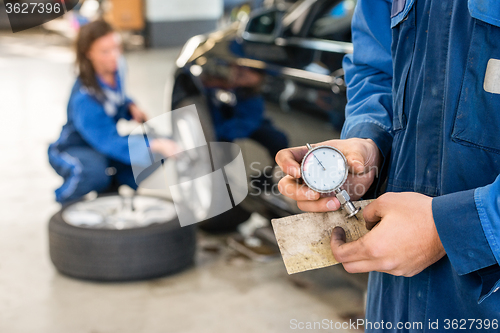 Image of Midsection Of Mechanic Holding Analog Gauge In Garage