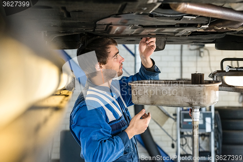 Image of Mechanic Examining Car At Garage