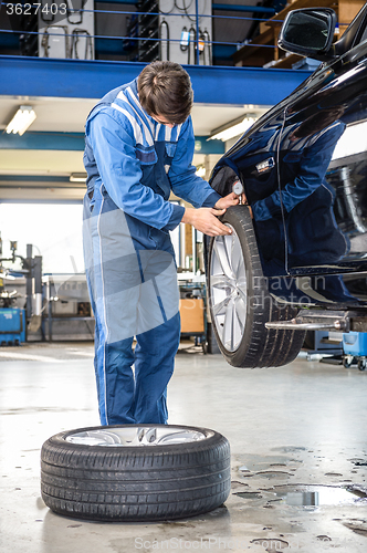 Image of Mechanic Pressing Gauge Into Tire Tread To Measure Its Depth