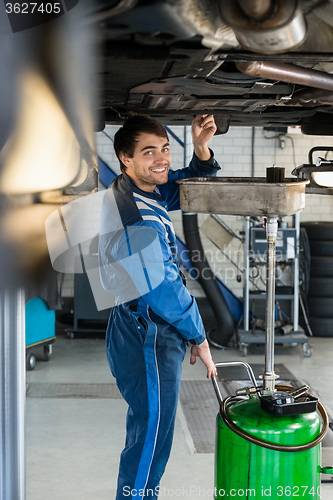 Image of Smiling Mechanic Repairing Car On Hydraulic Lift