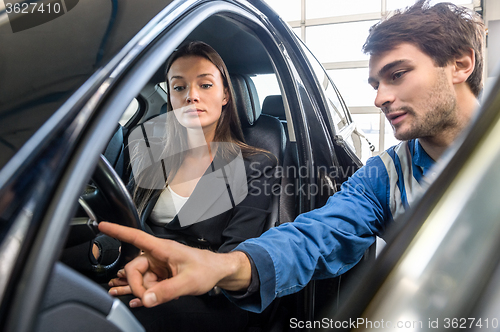 Image of Woman Looking At Mechanic Checking Light Switch Of Car