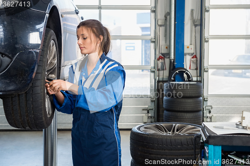 Image of Mechanic Changing Tire From Suspended Car