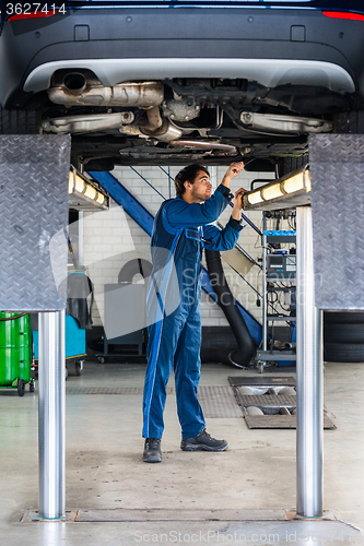 Image of Mechanic Examining Under The Car At Garage