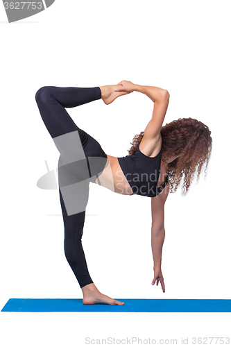 Image of Studio shot of a young fit woman doing yoga exercises.