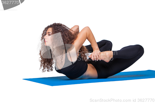 Image of Studio shot of a young fit woman doing yoga exercises.