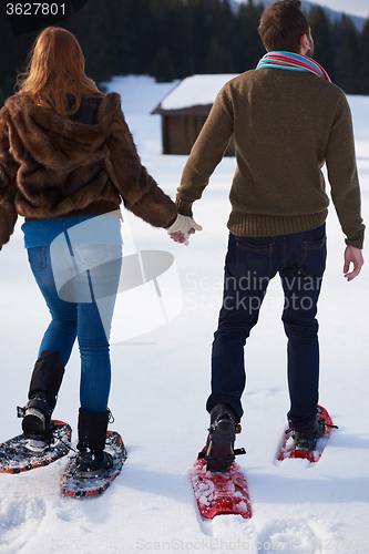 Image of couple having fun and walking in snow shoes