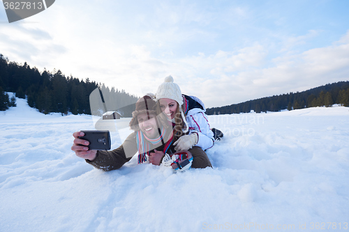 Image of romantic couple have fun in fresh snow and taking selfie