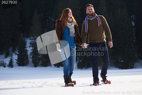 Image of couple having fun and walking in snow shoes