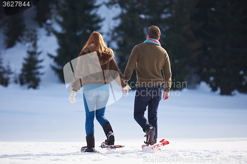 Image of couple having fun and walking in snow shoes