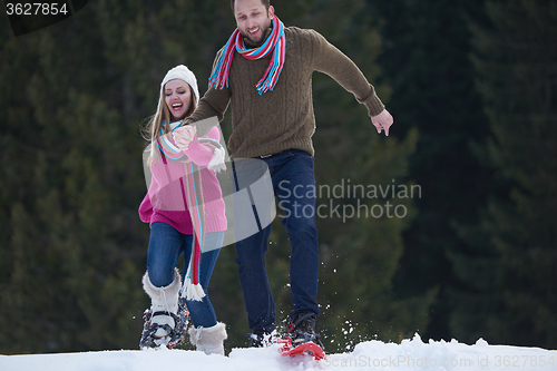 Image of couple having fun and walking in snow shoes