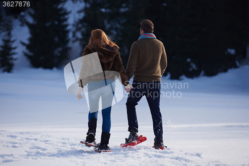 Image of couple having fun and walking in snow shoes