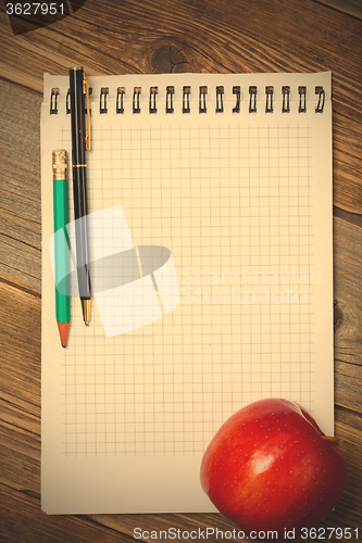 Image of scratchpad for taking notes, a pen, a pencil and an apple