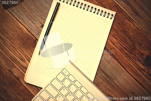 Image of Computer keyboard, notebook and pen