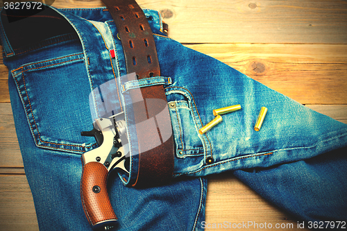 Image of revolver nagant with cartridges in old blue jeans