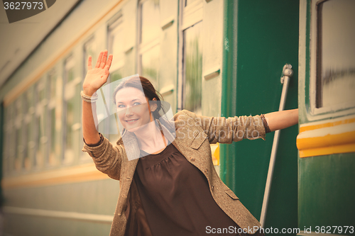 Image of smiling woman waving from the departing train