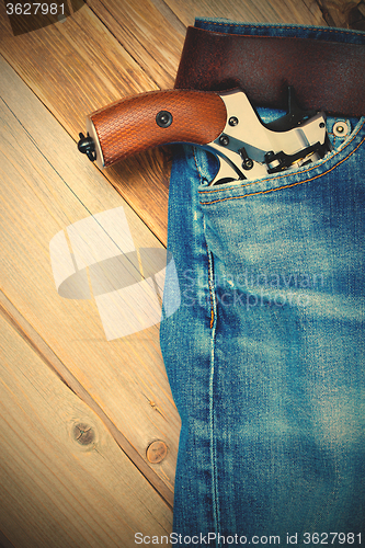 Image of revolver nagant in the pocket of old blue jeans