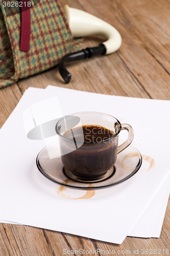 Image of Coffee cup, paper sheets and detective hat