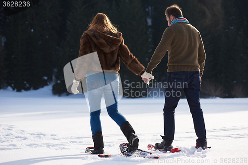 Image of couple having fun and walking in snow shoes