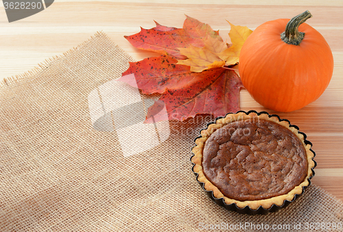 Image of Small pumpkin pie with gourd and autumn leaves