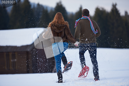 Image of couple having fun and walking in snow shoes