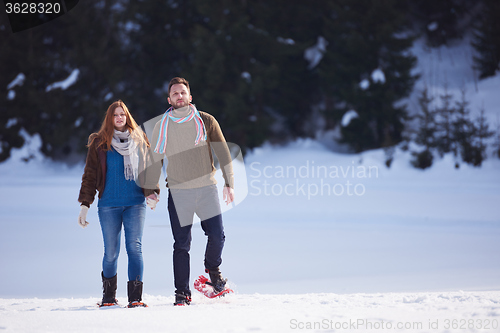 Image of couple having fun and walking in snow shoes