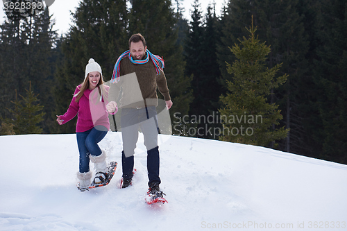 Image of couple having fun and walking in snow shoes