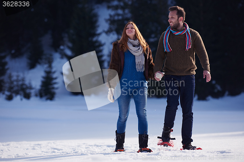 Image of couple having fun and walking in snow shoes