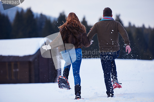 Image of couple having fun and walking in snow shoes