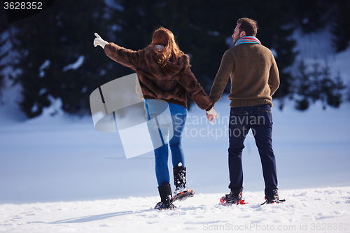 Image of couple having fun and walking in snow shoes