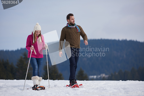 Image of couple having fun and walking in snow shoes