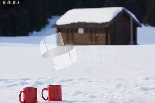 Image of two red coups of hot tea drink in snow  at winter