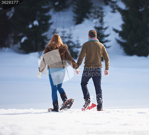 Image of couple having fun and walking in snow shoes