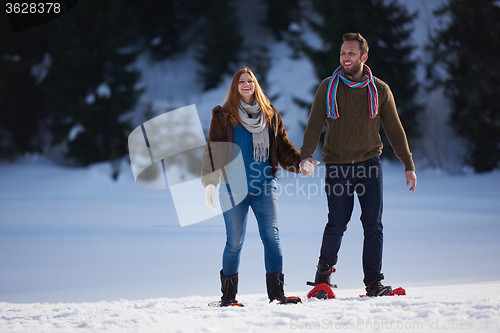 Image of couple having fun and walking in snow shoes