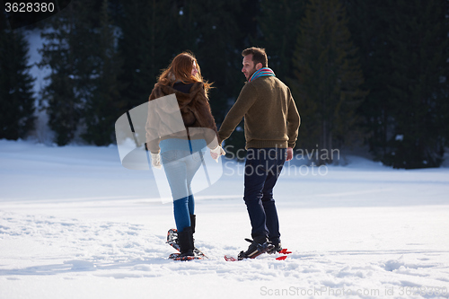 Image of couple having fun and walking in snow shoes