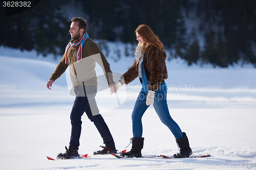 Image of couple having fun and walking in snow shoes