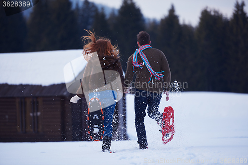 Image of couple having fun and walking in snow shoes