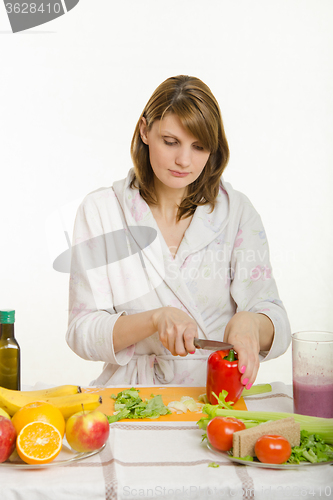 Image of Young woman cuts sweet pepper vegetarian cooking Salad