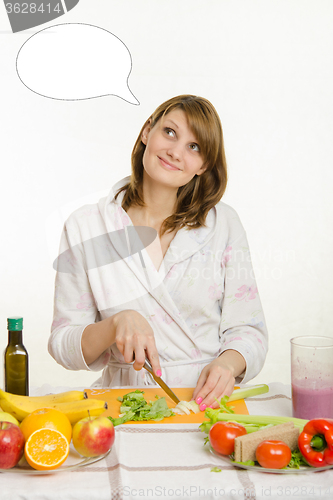 Image of Housewife cuts vegetables for salad and dreamy looks at a cloud over his head thoughts