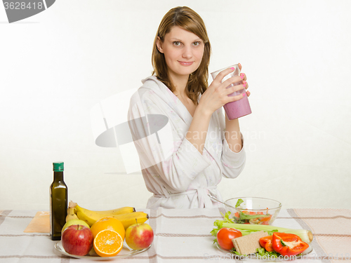 Image of Young girl sitting at the kitchen table with a fruit milkshake in hand