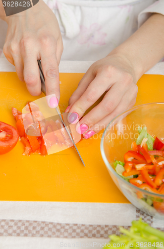 Image of Girl cuts a tomato for a vegetable salad