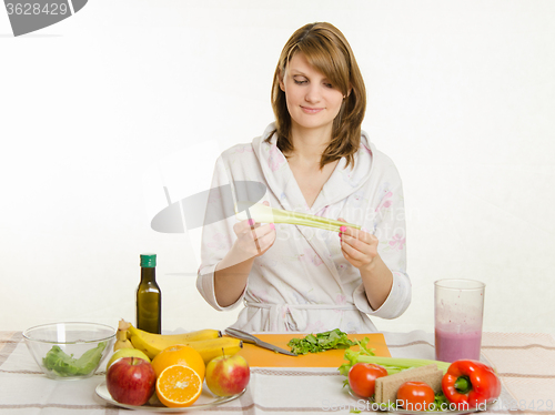Image of Happy housewife holding cooking celery salad