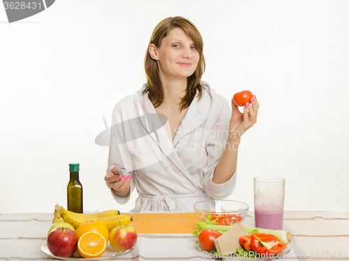 Image of Happy housewife picked up a tomato salad cooking
