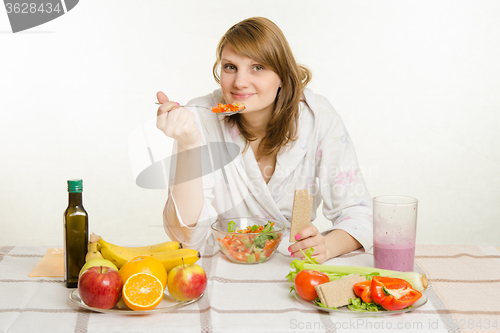 Image of Young girl eats vegetarian vegetable salad with bread roll