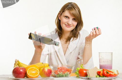 Image of Young girl pours oil into a vegetarian vegetable vitamin salad