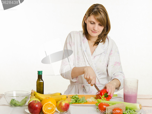 Image of Young girl cuts pepper vegetarian salad