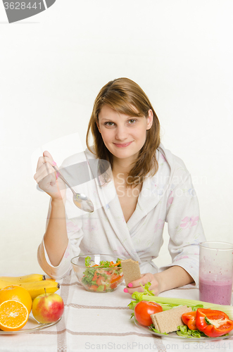 Image of Young girl eating a vegetarian salad at the table