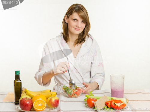 Image of Young girl stirs cooked vegetarian vegetable salad