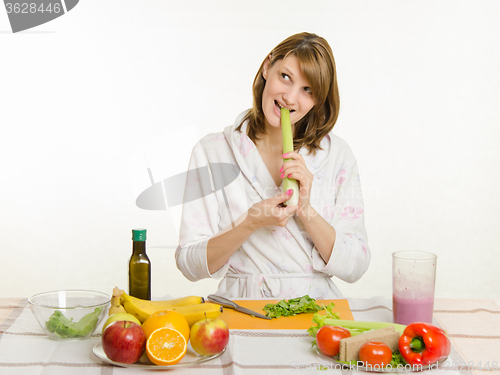 Image of Happy housewife biting celery and looking up