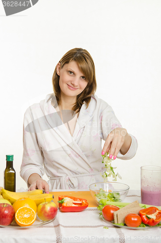 Image of Housewife throws chopped celery in a bowl of salad