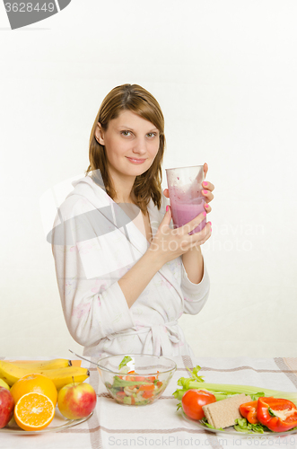 Image of Young girl sitting at the kitchen table, drinking a vitamin milkshake